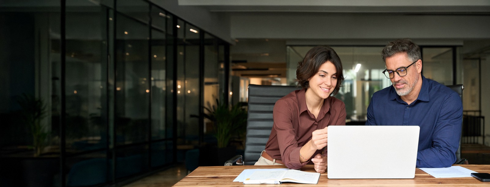 Two colleagues smiling at a laptop at a shared desk